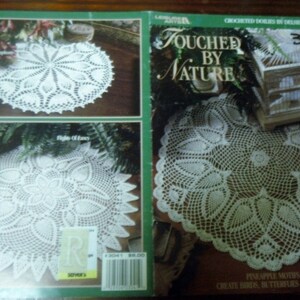 May include: A book cover featuring white crocheted doilies with intricate floral and geometric patterns. The title "Touched by Nature" is displayed, along with the number 3041. The cover also includes the text "Create Birds, Butterflies & Florals."