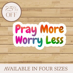 May include: A sticker with the text "Pray More Worry Less" in a rainbow gradient. A circular label in the upper left corner reads "25% OFF". The bottom of the image states "AVAILABLE IN FOUR SIZES". The background is a wood grain pattern.