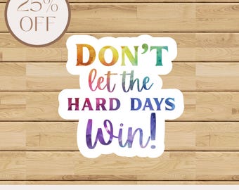 May include: A sticker with the text "DON'T let the HARD DAYS Win!" in colorful watercolor lettering. A circular label in the upper left corner reads "25% OFF". The sticker is on a wooden background. Available in four sizes.