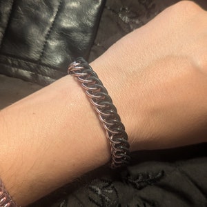 May include: A black and rose gold chain bracelet with a double row of links.