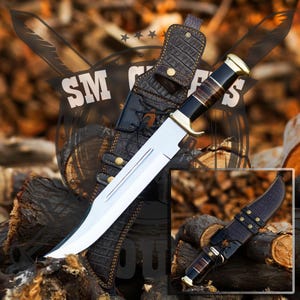 May include: A large, silver-colored hunting knife with a brown leather sheath. The knife has a brass handle with a wood inlay. The sheath has a decorative pattern and a strap.