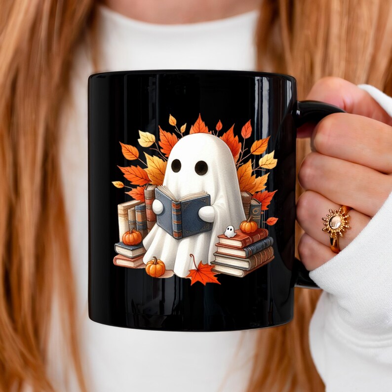 May include: Black ceramic mug featuring a cartoon ghost reading a book, surrounded by autumn leaves, pumpkins, and stacks of books. The design has a Halloween and fall theme.
