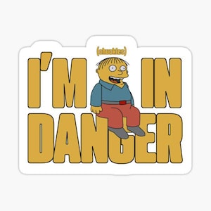 May include: A yellow cartoon character with a blue shirt and red pants sits on a yellow background. The text "I'm in danger" is written in yellow letters with the word "chuckles" in parentheses above the character.