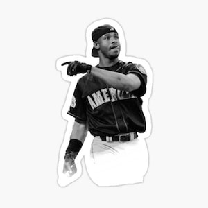 May include: Black and white sticker of a baseball player in a dark jersey with "AMERICA" across the chest. He wears a black cap, batting gloves, and wristbands, pointing with his left hand. The player is wearing white pants and a black belt.