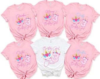 May include: Pink and white t-shirts featuring unicorn designs and the number 3. The shirts display text such as "Grandma", "Mommy", "Daddy", "Sister", "Birthday Girl", and "Brother". These are birthday-themed shirts.