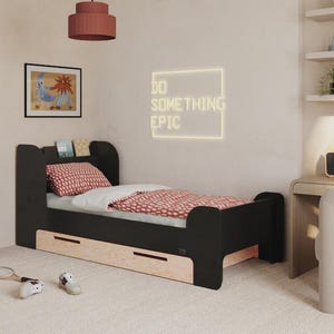 Può includere: Un moderno letto nero con base in legno chiaro e due cassetti. Il letto è composto da un piumino e un cuscino a fantasia rossa. Un quadro incorniciato e un'insegna al neon con la scritta "DO SOMETHING EPIC" sono sulla parete.