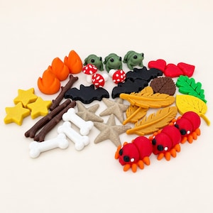 May include: A collection of small, colourful polymer clay charms including orange flames, green frogs, red and white mushrooms, black bats, yellow stars, brown twigs, white bones, tan starfish, gold feathers, red hearts, green and yellow leaves, and red spiders.