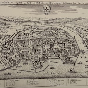 Może przedstawiać: Czarno-biały historyczny miedzioryt zatytułowany Eigentliche Contrafactur der Statt Costantz am Bodensee wie solche waeender Belagerung Anno 1633. im wesen gestanden. Obraz przedstawia plan ufortyfikowanego miasta z budynkami, rzeką i łodziami.