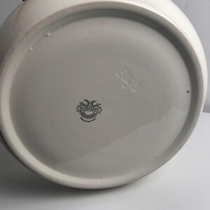 May include: A white ceramic bowl base featuring a black printed Villeroy & Boch logo with an eagle emblem and the text Made in Saar-Basin. The underside also includes an embossed mark with the characters 2KG 3 on the smooth, glazed surface.