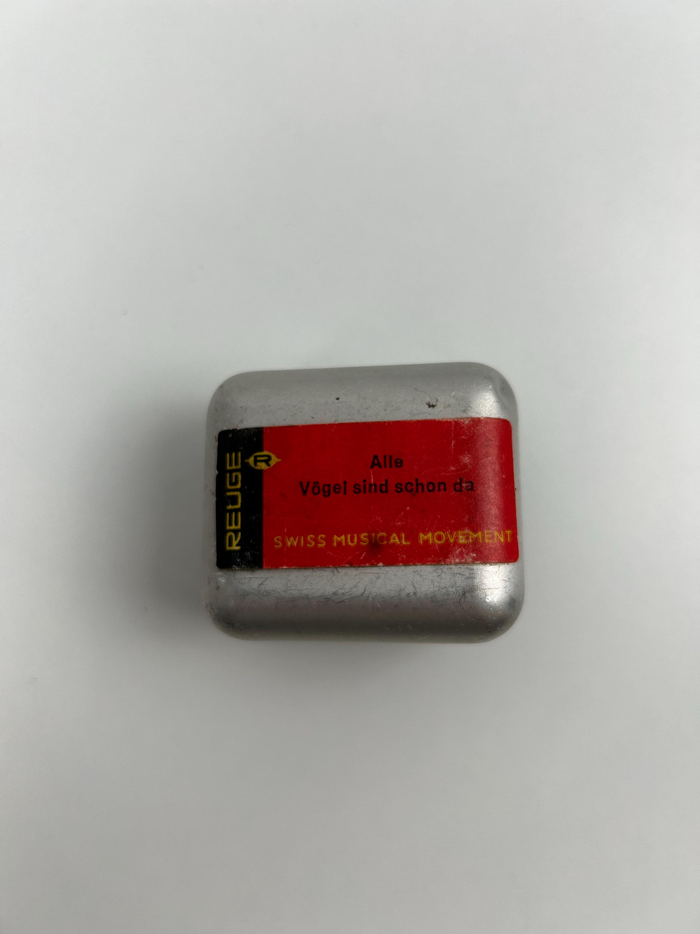 Vintage REUGE Spieluhr‑Werk in silberfarbenem Metallgehäuse mit rotem Originaletikett „Alle Vögel sind schon da – Swiss Musical Movement“