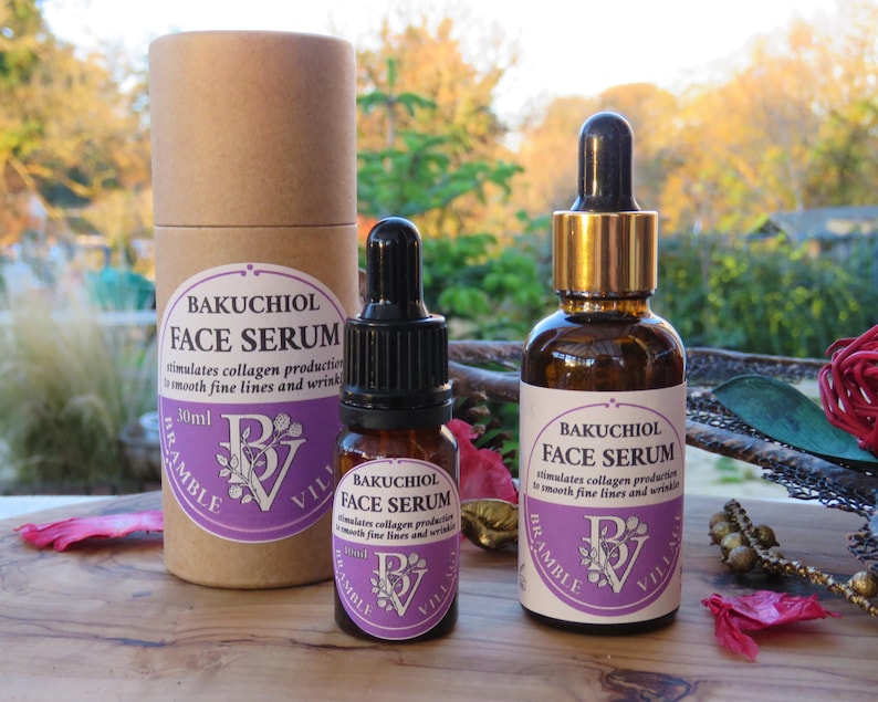May include: Two brown glass bottles of Bakuchiol Face Serum with black droppers and gold accents, and a cylindrical cardboard container. The labels are white with purple accents and text. The serum is designed to stimulate collagen production.