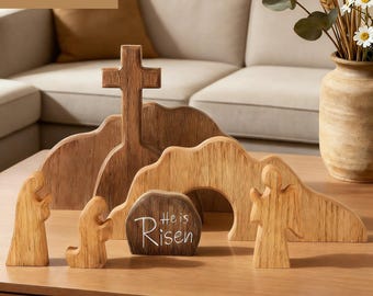 May include: Wooden Easter scene set with a cross, figures, and a tomb with the text "He is Risen." The set includes a cross, figures, and a tomb, all crafted from wood. The scene is set on a wooden table, with a neutral background.