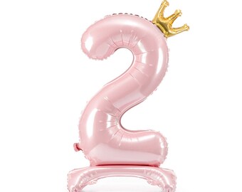 May include: Pink number two balloon with a gold crown on top. The balloon is standing upright on a base.