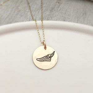 May include: Gold necklace with a round pendant featuring a winged shoe design.