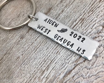 May include: Silver keychain with a rectangular tag that reads "Aiden West Geauga HS 2022" with a running shoe icon.
