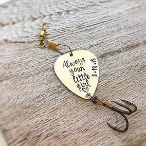 May include: Gold-coloured fishing lure with a heart and the text "Always your little girl 8.18.18" engraved on it.