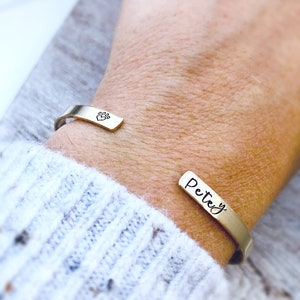 May include: A gold-toned cuff bracelet with a paw print charm and the name "Petey" engraved on the other side.