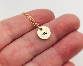 May include: A gold necklace with a small round pendant featuring a sunburst design.