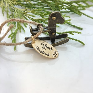 Puede incluir: Adorno de caballo de balancín dorado con una etiqueta que dice "Julian's 1st Christmas 2018".