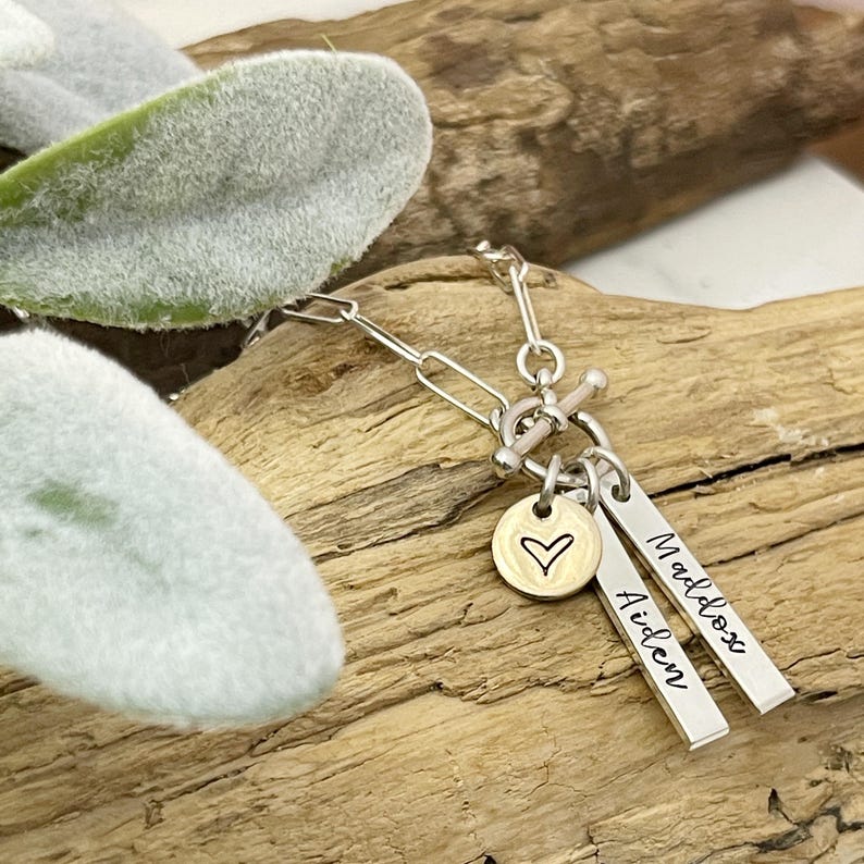 May include: Silver necklace with a heart charm and two personalized tags that read "Maddox" and "Aiden".