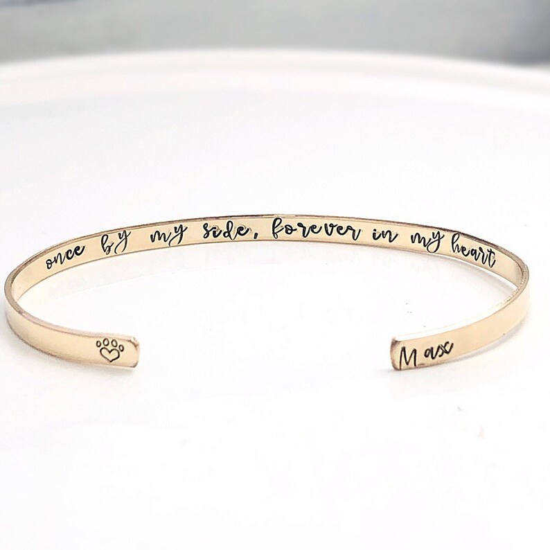 Pu&ograve; includere: Braccialetto rigido in oro con l'iscrizione "once by my side, forever in my heart" e un'impronta di zampa con un cuore all'interno. Il nome "Max" &egrave; inciso sull'altro lato.