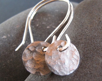May include: A pair of silver earrings with hammered round discs hanging from simple wire loops.