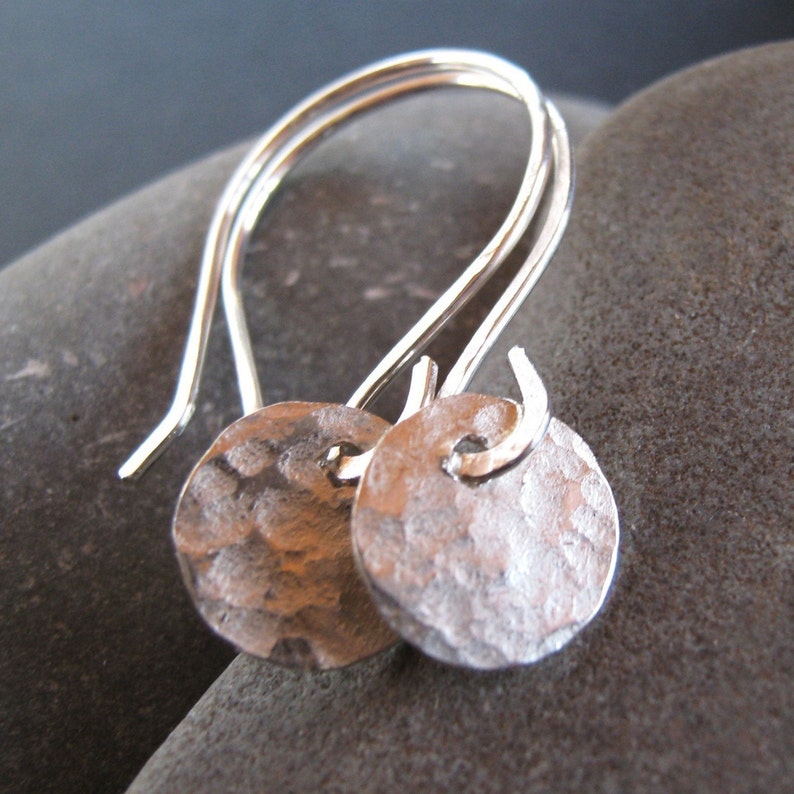 May include: A pair of silver earrings with hammered round discs hanging from simple wire loops.