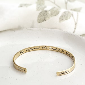 May include: Gold bangle bracelet with the inscription "She believed she could, so she did" and the name "Julie" engraved on the inside.