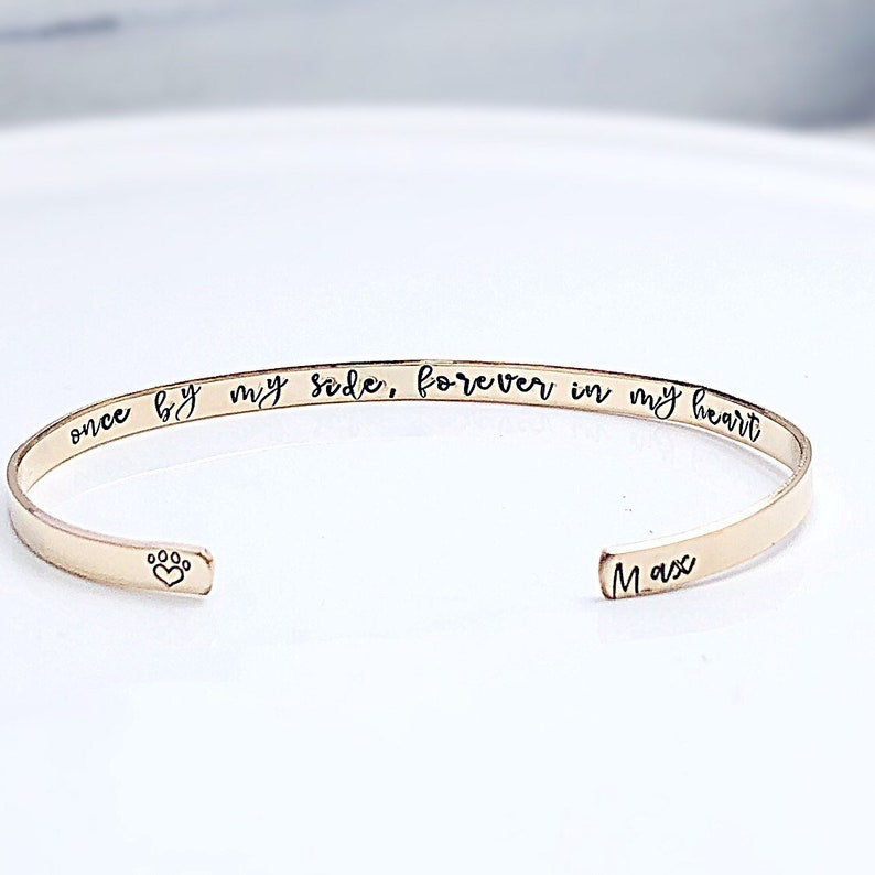 Pu&ograve; includere: Braccialetto rigido dorato con l'iscrizione "once by my side, forever in my heart" e il nome "Max" inciso sul lato. Un piccolo segno di zampa con un cuore &egrave; inciso sull'altro lato.