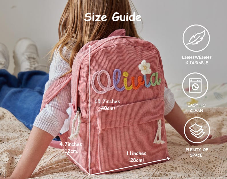 以下が含まれることがあります： カラフルな刺繍文字で「Olivia」と書かれ、白い花のアップリケが付いたピンクのコーデュロイ製バックパック。バッグのサイズは高さ40cm、幅28cm、奥行き12cmです。フロントポケットと白いロープのジッパープルが付いています。