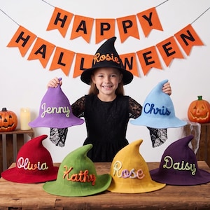 May include: A collection of seven pointed witch hats in various colors including black, purple, light blue, red, green, yellow, and dark purple. Each hat features a personalized name embroidered in a contrasting yarn color on the front.