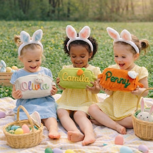 May include: Three rectangular corduroy pouches in white, green, and orange, each featuring embroidered names: Olivia, Camila, and Penny. The pouches are accented with small plush carrot or bunny motifs and are held by children wearing white bunny ear headbands.