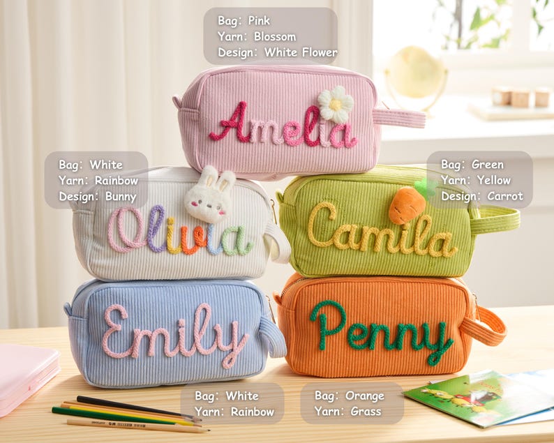 May include: Five rectangular corduroy pencil cases in pink, white, green, blue, and orange. Each case features a personalized name embroidered in yarn with decorative accents: a white flower, a bunny, a carrot, and plain lettering.