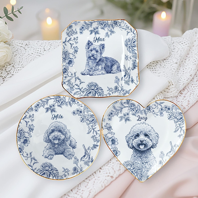 May include: Three decorative plates with blue floral designs and gold rims. Each plate features a different dog breed illustration and a name: Max, Mila, and Lucy. The plates are in square, round, and heart shapes.