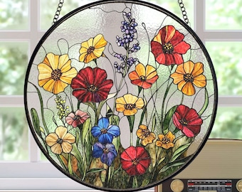 May include: A round stained glass window featuring a colorful floral design with red, yellow, and blue flowers. The window is framed in black metal and hangs from a chain.