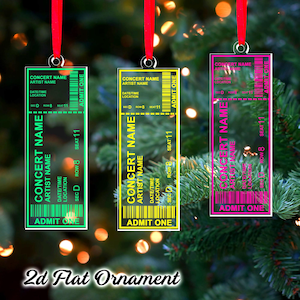 May include: Three concert ticket-shaped Christmas ornaments with red ribbons. The ornaments are in green, yellow, and pink, each with a different color border and text. The text includes "CONCERT NAME", "ARTIST NAME", and "ADMIT ONE".