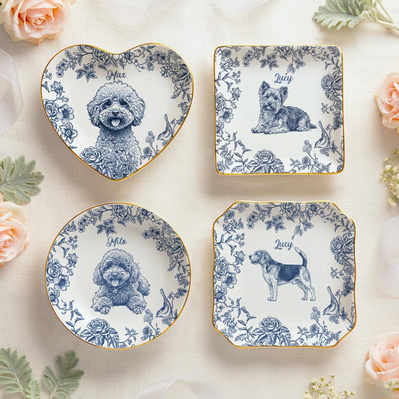 May include: Four decorative ceramic plates with blue floral designs and gold rims. Each plate features a different dog breed illustration and a name: Max, Lucy, Mila, and Lucy. The plates are in heart, square, and round shapes.