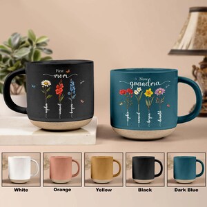 May include: Set of 10 ceramic mugs in various colours, including white, orange, yellow, black, and dark blue. Each mug features a floral design with the text "First Mom" or "Now Grandma" and a list of names.