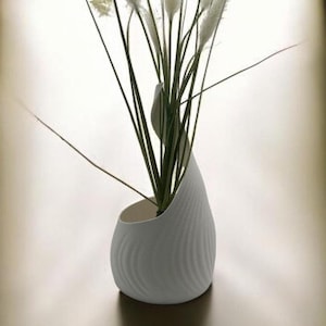 Peut inclure: Vase en céramique blanche avec un design texturé et ondulé, contenant un bouquet de pampas séchées blanches.