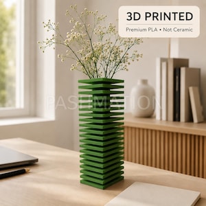May include: A 3D printed green vase with a stacked square plate design, holding delicate white baby's breath flowers. The vase features the text 3D PRINTED Premium PLA • Not Ceramic. The structure consists of multiple horizontal layers.