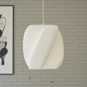 May include: A white, modern pendant light fixture with a unique, textured design. The light has a spiral pattern and hangs from a white cord. The fixture is in front of a gray brick wall.