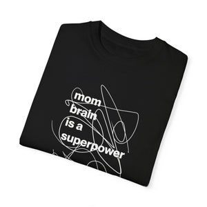 May include: Black t-shirt with white text that reads "mom brain is a superpower" with a white squiggly line design.