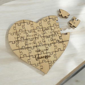 Könnte beinhalten: Ein Puzzle aus Holz in Herzform mit der Aufschrift "Du bist das fehlende Puzzleteil meines Herzens! Lass uns gemeinsam durchs Leben puzzeln, ein Stück nach dem anderen. Froher Valentinstag. Mit Liebe, Vanessa."