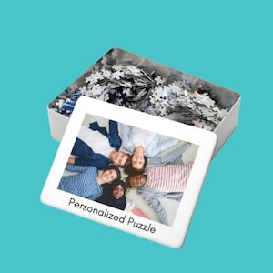 May include: A white box with a personalized puzzle inside. The box has a clear plastic window showing the puzzle pieces. The puzzle is a photo of a group of friends smiling and lying on their backs in a circle. The box has the text "Personalized Puzzle" printed on the front.