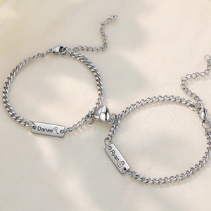 May include: Two silver chain bracelets with heart charms and personalized name tags that read "Danae" and "Ryan".