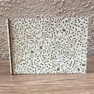 Álbum de fotos mini de 4 x 6: notas musicales doradas sobre fondo crema plano, cartón fino/caja de cereales, formato horizontal
