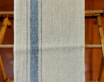 May include: A beige linen tea towel with blue stripes hanging on a wooden drying rack.