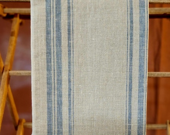 May include: A beige linen tea towel with blue stripes. The towel is hanging on a wooden drying rack.