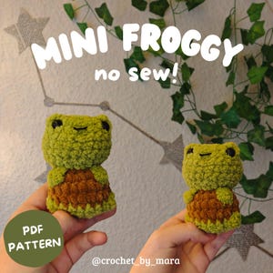 Könnte beinhalten: Zwei kleine, handgefertigte Häkelfrösche mit grünen Köpfen und braunen Körpern. Die Frösche haben schwarze Sicherheitsaugen und einen aufgestickten Mund. Der Text "MINI FROGGY no sew!" steht oben, "PDF PATTERN" in einem grünen Kreis unten links.