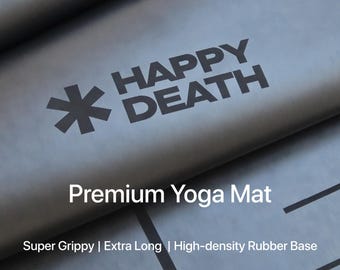 May include: A black yoga mat with the words "HAPPY DEATH" and a starburst logo printed on it. The text "Premium Yoga Mat" is displayed below, along with "Super Grippy | Extra Long | High-density Rubber Base".